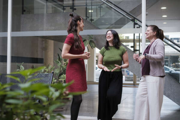 Drei Frauen stehen im Innenhof eines Bürogebäudes und unterhalten sich.