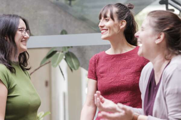 Drei Frauen sind in einem Gespräch und lachen sich gegenseitig an.