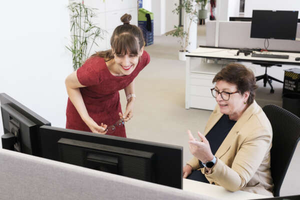 Zwei Frauen im Büro gucken auf einen Bildschirm.