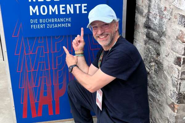 Ein Mann hockt vor einem Plakat mit der Aufschrift "Neue Kapitel" und "Neue Momente".