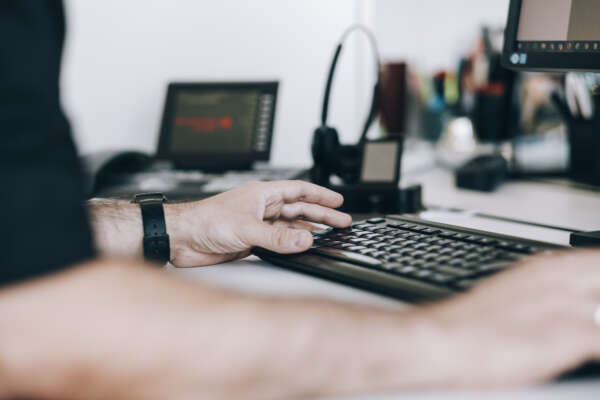 Blick über den Arm auf Hände an einer Tastatur.