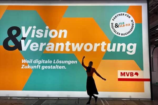 Eine Person steht vor einer Messewand mit dem Slogan Vision und Verantwortung.