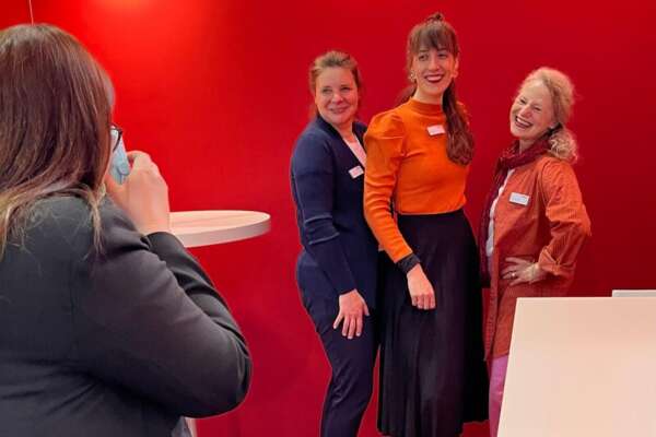 Das VLB-TIX Vertriebsteam posiert lachend vor einer Wand.