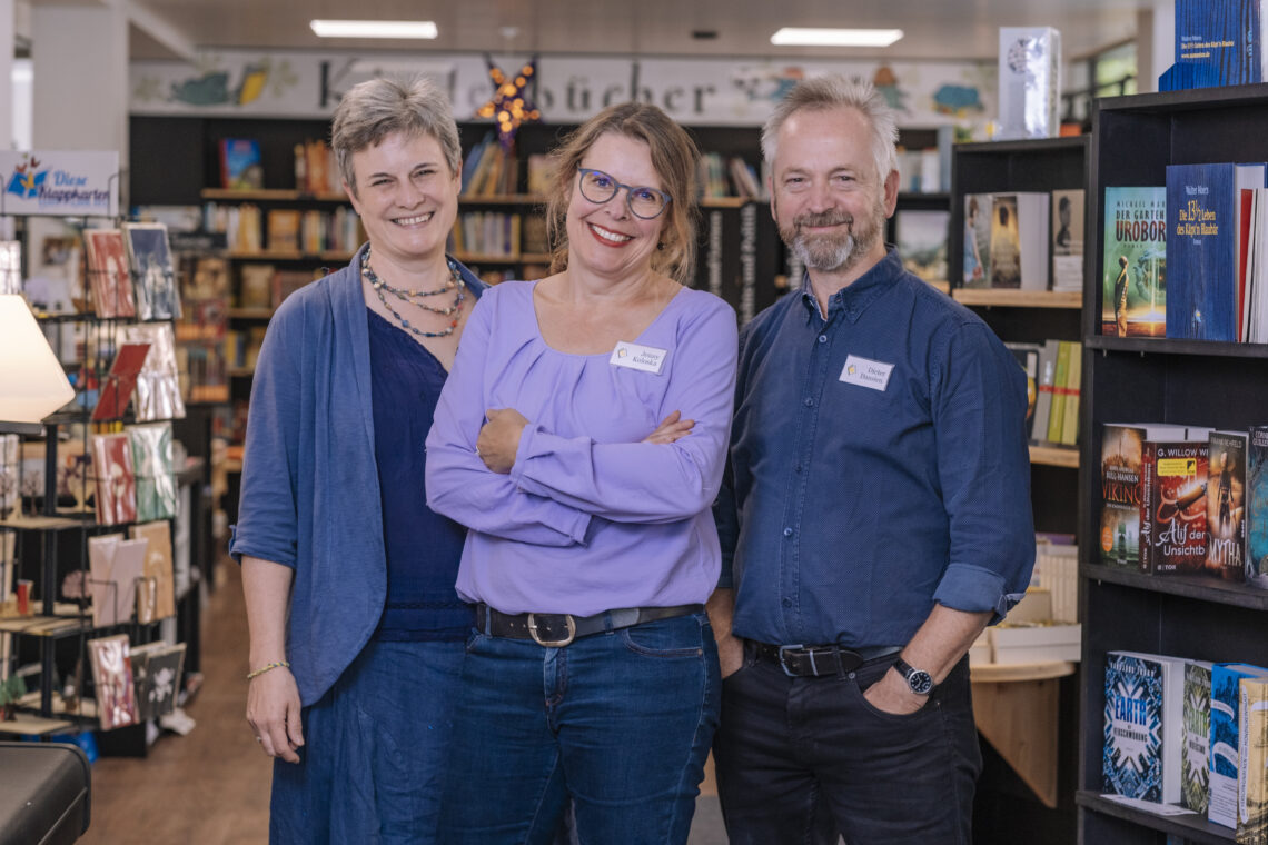 Zwei Frauen und ein Mann stehen in einer Buchhandlung.