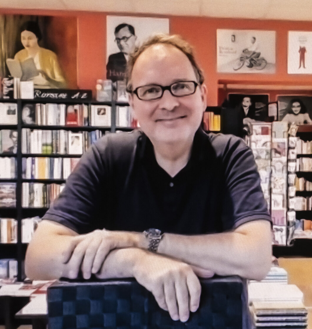 Lächelndes Bild von Klaus Kowalke vor einem Bücherregal.